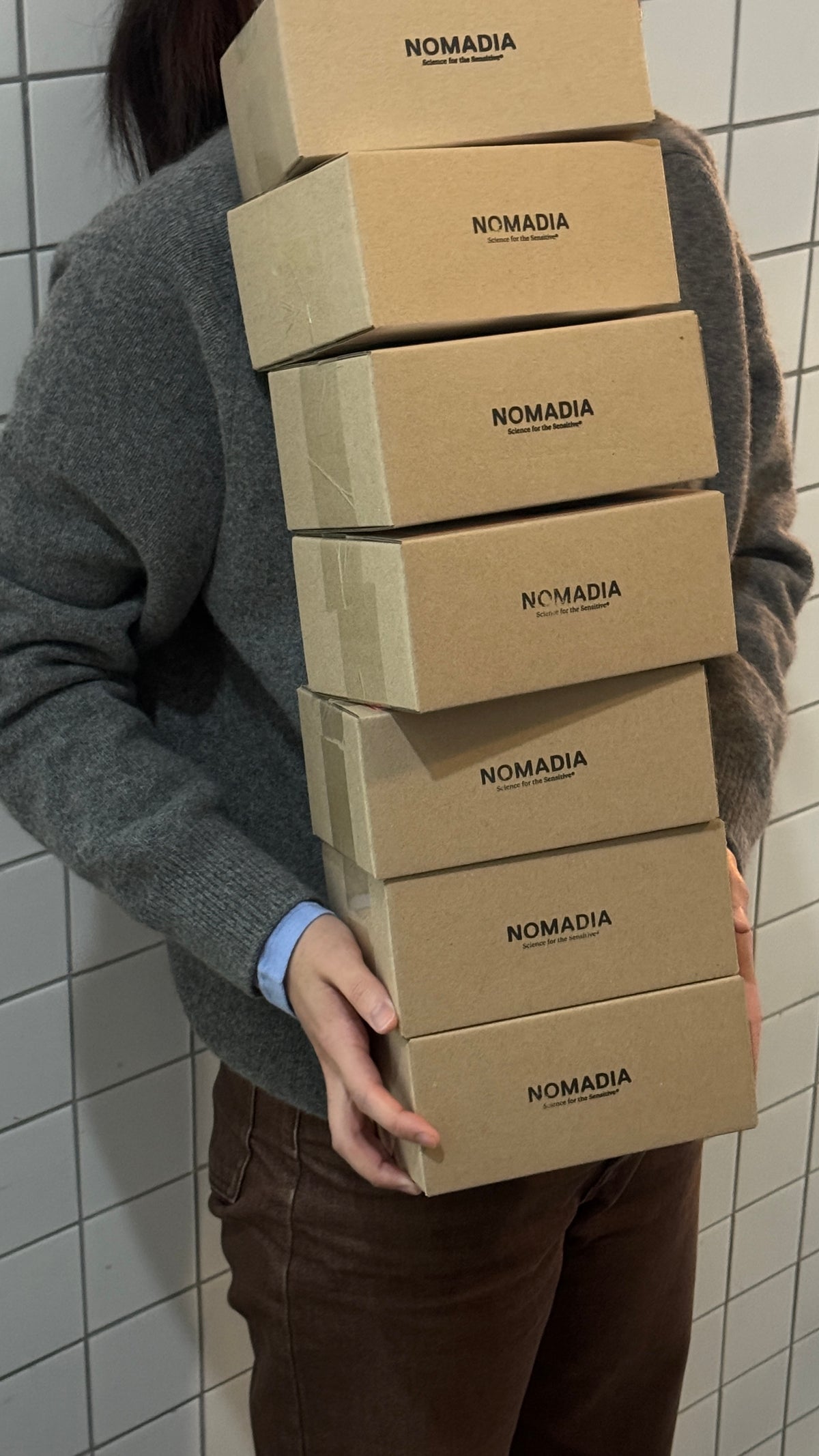 Person holding a stack of NOMADIA shipping boxes